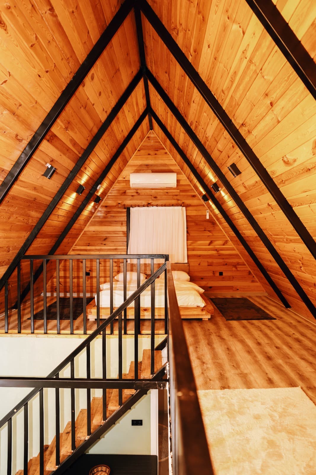 A-frame çatı katı: ahşap tavan, siyah çelik korkuluklar ve loft yatak odası