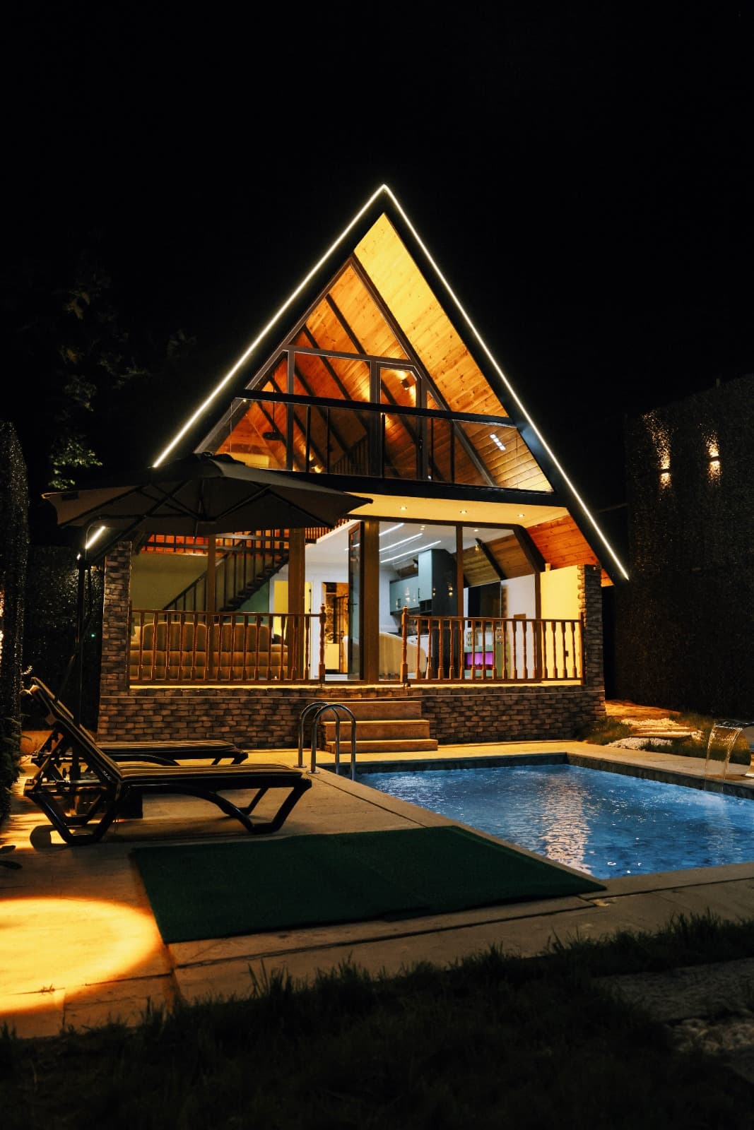 Villa, havuz ve şezlong alanının geniş açılı gece görünümü